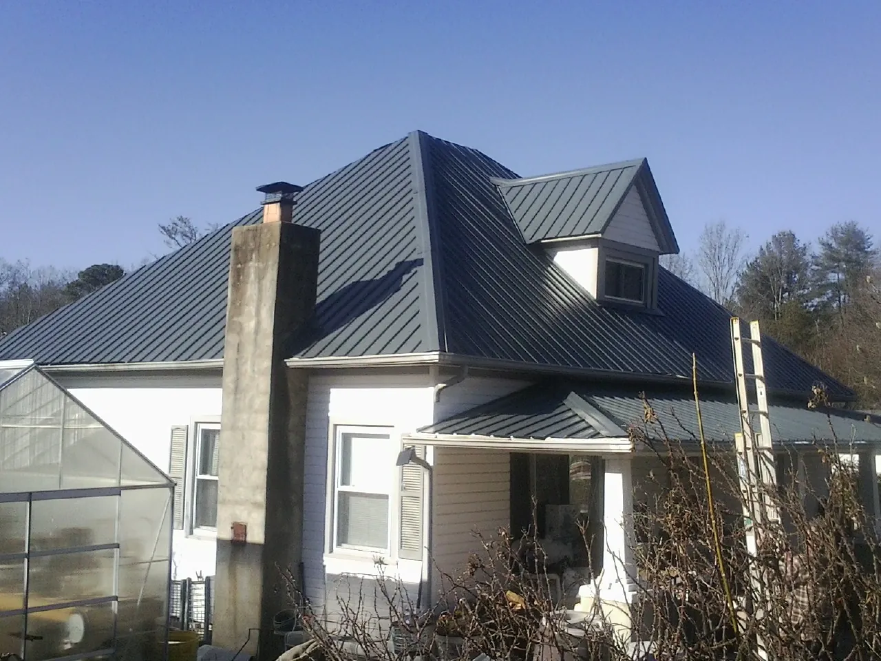 Dark blue standing seam metal roof on a white farmhouse with dormer — Slate & Tile Roof Repair by Roofing Brothers in Shinnston