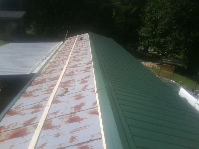 Old rusted panels beside newly installed green metal roofing — Wind Damage Roof Repair by Roofing Brothers in Shinnston
