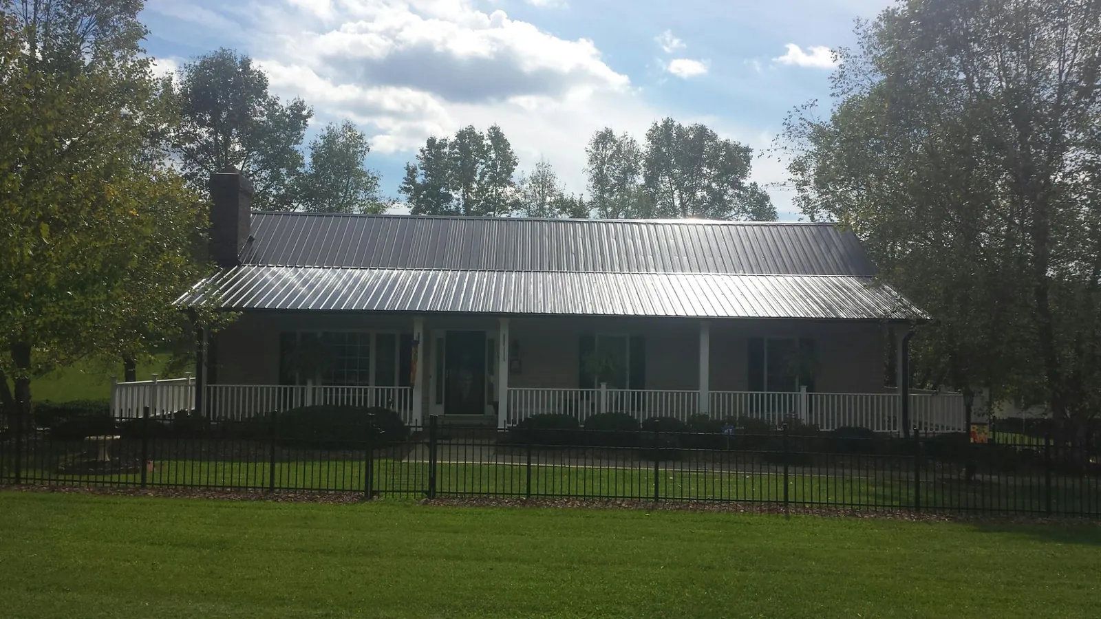 Gray metal roof on a brick ranch with a full width front porch — Gutter Guard Installation work by our crew in Shinnston