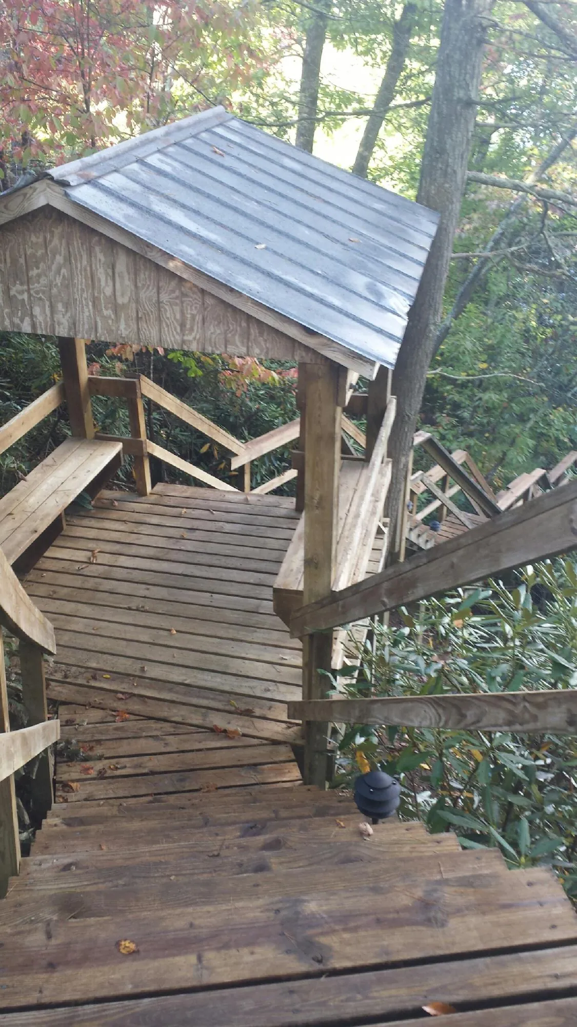 Metal roofed shelter over wooden steps on a wooded walkway — Skylight Repair & Installation work by our crew in Shinnston