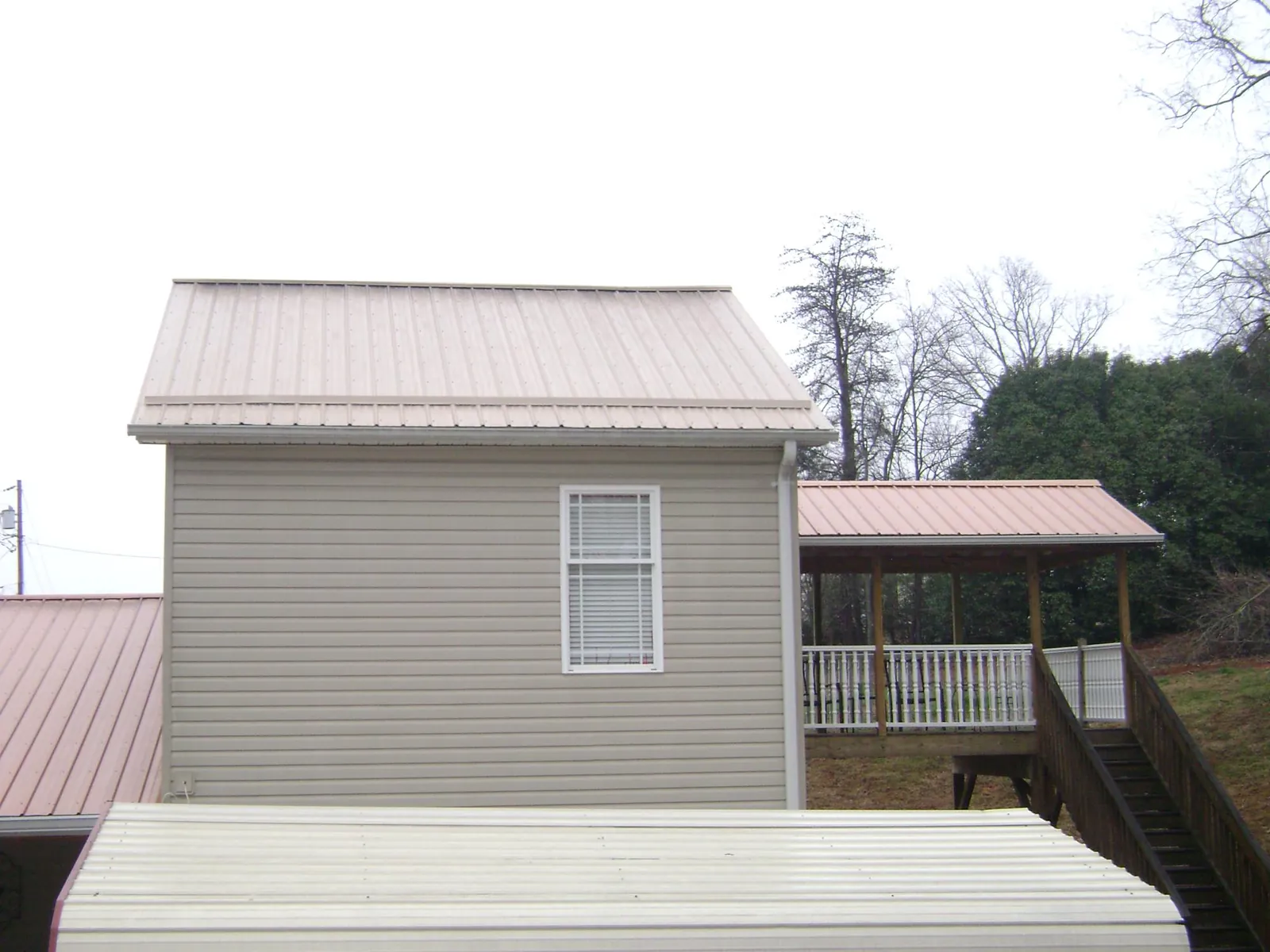 Tan metal roofs on a two story addition and attached porch, from a Roof Replacement job in Shinnston