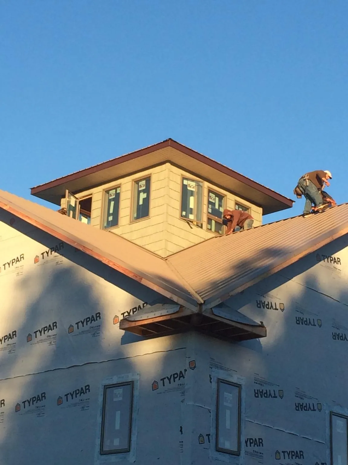 Roofers working around a rooftop cupola on a new metal roof at sunset — Roof Waterproofing in Shinnston by Roofing Brothers